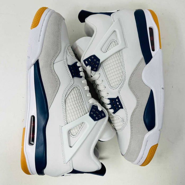 The Jordan 4 Retro SB Navy from Holy Ground Sneaker Shop, with white and navy mesh and orange details, sits on a pristine box showcasing the Nike SB logo. Its cushioned heel ensures its a perfect accessory addition.