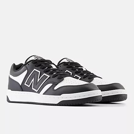 New Balance 480 sneakers in black and white leather with a perforated toe box, side view.