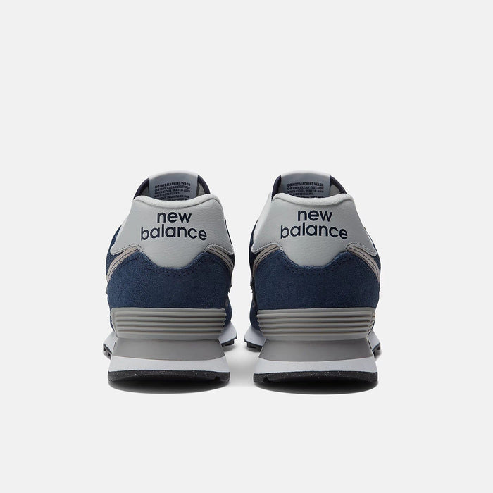 New Balance 574 Core sneakers back view showing heel design with navy blue suede, gray accents, and textured midsole.