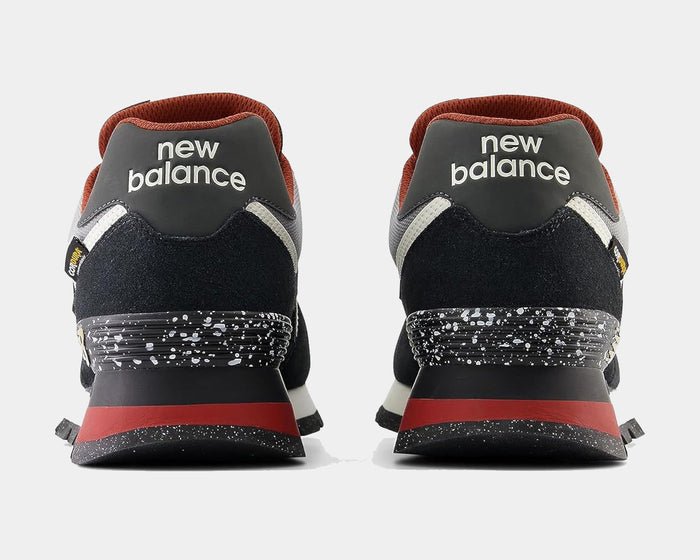 New Balance 574 Rugged sneakers back view showcasing black suede uppers, red accents, and speckled heel detailing.