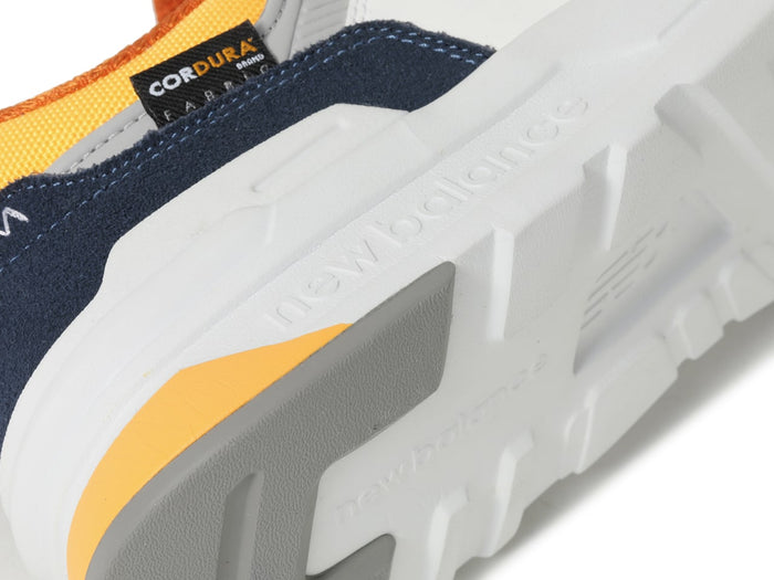 New Balance 997H sneakers with a durable Cordura fabric upper in navy blue, yellow, and white, outsole close-up view.