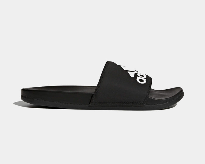 Adidas Adilette Comfort Slides in black with logo-adorned synthetic strap and cushioned footbed, side view.