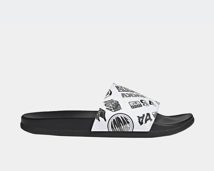 Adidas Adilette Comfort Slides in black with white strap featuring black graphic designs, side view.