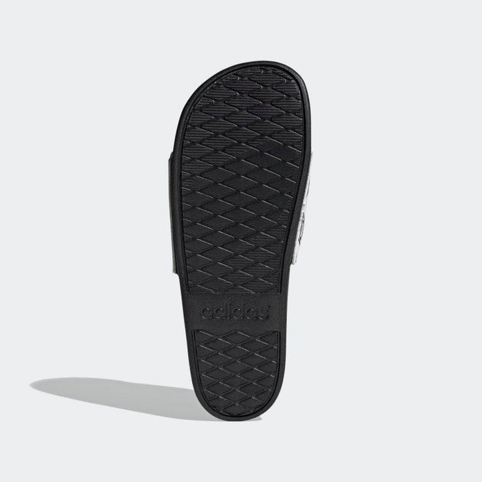 Adidas Adilette Comfort Slides black rubber outsole with textured tread pattern and embossed brand logo, sole/bottom view.