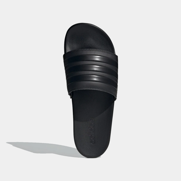 Adidas Adilette Comfort Slides in black with textured footbed and striped synthetic upper, top view.