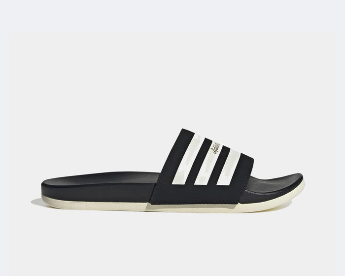 Adidas Adilette Comfort slides in black with white stripe detail and contoured footbed, side view.