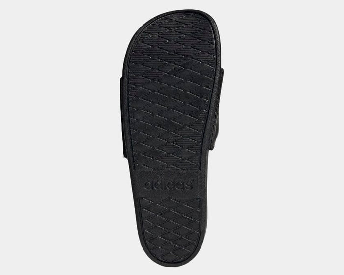 Adidas Adilette Comfort sandals black outsole with textured grip pattern and embossed Adidas logo, bottom view.