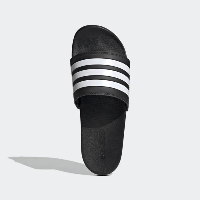 Adidas Adilette Comfort slides in black with iconic white three-stripe strap design, top view showing textured footbed.