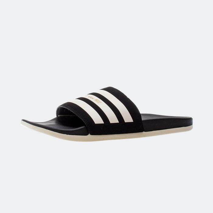 Adidas Adilette Comfort sandals in black with white stripes and a soft cushioned sole, side angle view.