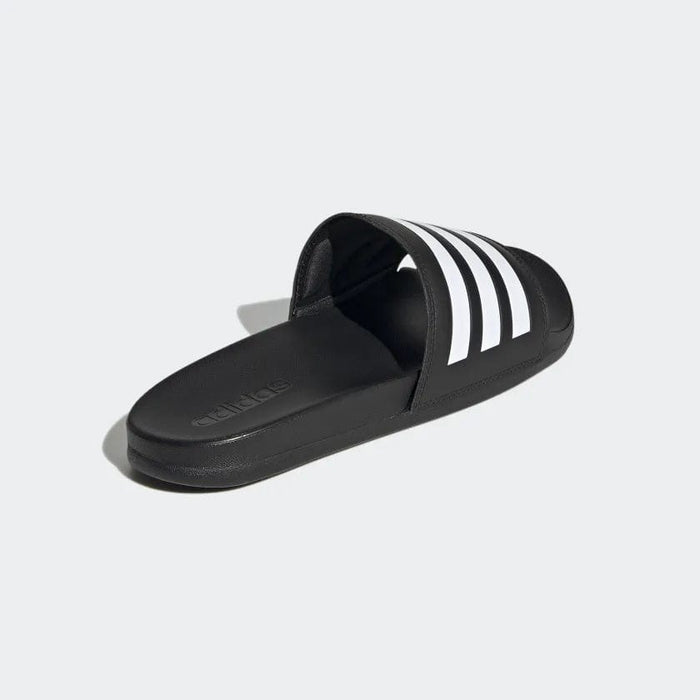 Adidas Adilette Comfort slides in black with white stripe detail, featuring contoured footbed and lightweight design, angled side view.