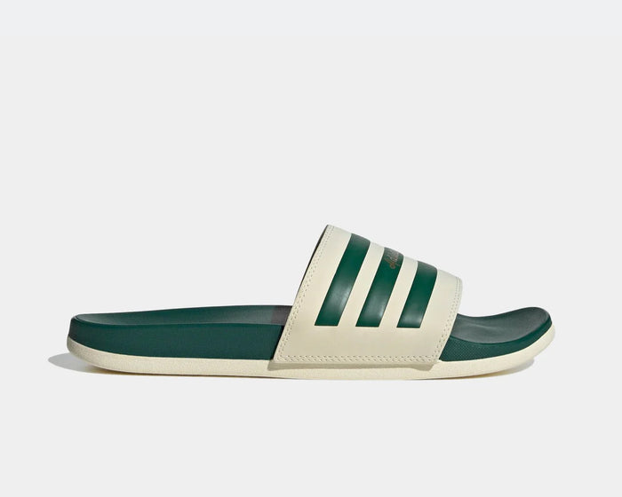 Adidas Adilette Comfort slides in cream and dark green with signature stripe design and contoured footbed, side view.