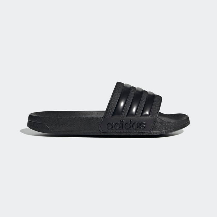 Adidas Adilette Shower Slides in solid black with textured footbed and three-stripe design on the band, side view.