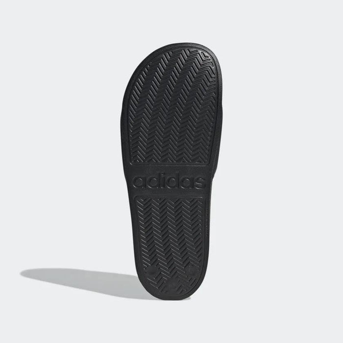 Adidas Adilette Shower Slides sole view in black showing herringbone tread pattern and embossed Adidas logo.