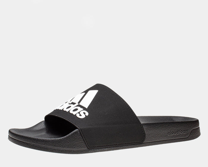 Adidas Adilette Shower Slides in black with white logo, featuring Cloudfoam footbed and textured outsole, side view.