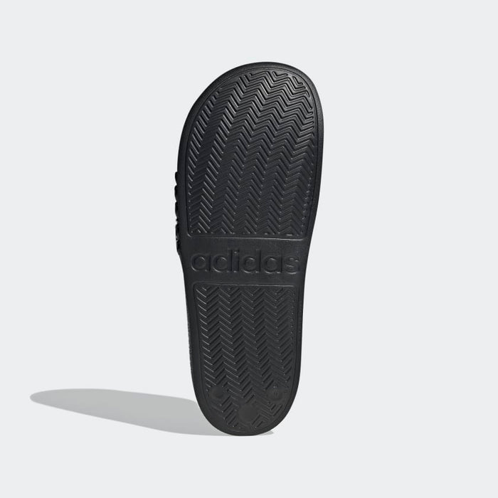 Adidas Adilette Shower Slides outsole in black showing textured herringbone traction pattern and embossed logo, sole/bottom view.