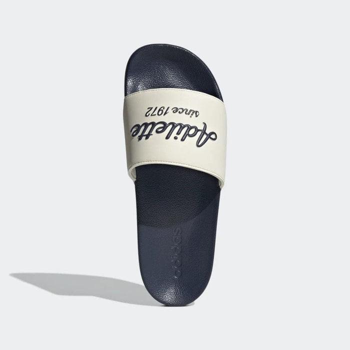 Adidas Adilette Shower Slides in navy blue with cream strap featuring "Adilette since 1972" text in navy, top view.