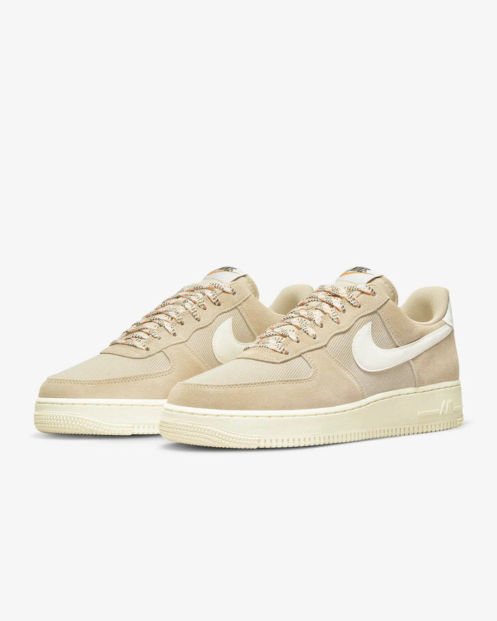 Nike Air Force 1 '07 LV8 sneakers in beige with white leather Swoosh, textured suede overlays, and patterned laces, front angle view.