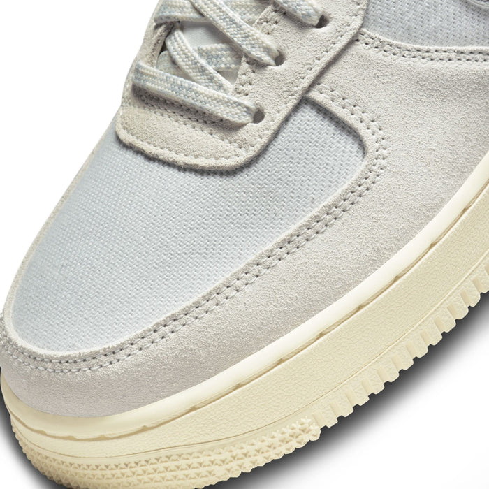 Nike Air Force 1 '07 LV8 sneakers with light gray suede overlays, mesh upper, and cream-colored sole, close-up of toe box.