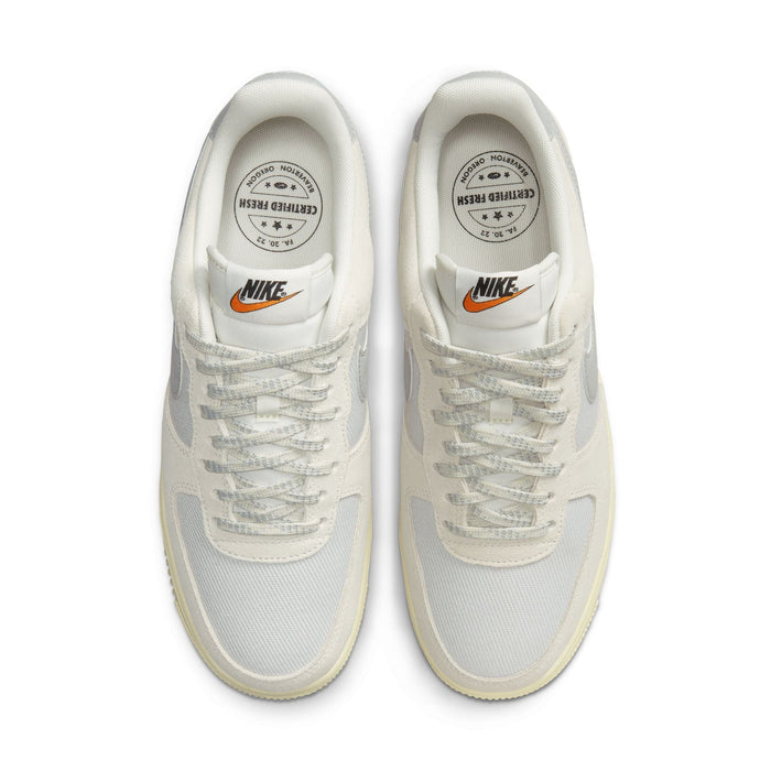 Nike Air Force 1 '07 LV8 sneakers in white with mesh upper, textured laces, and orange logo detailing, top view.