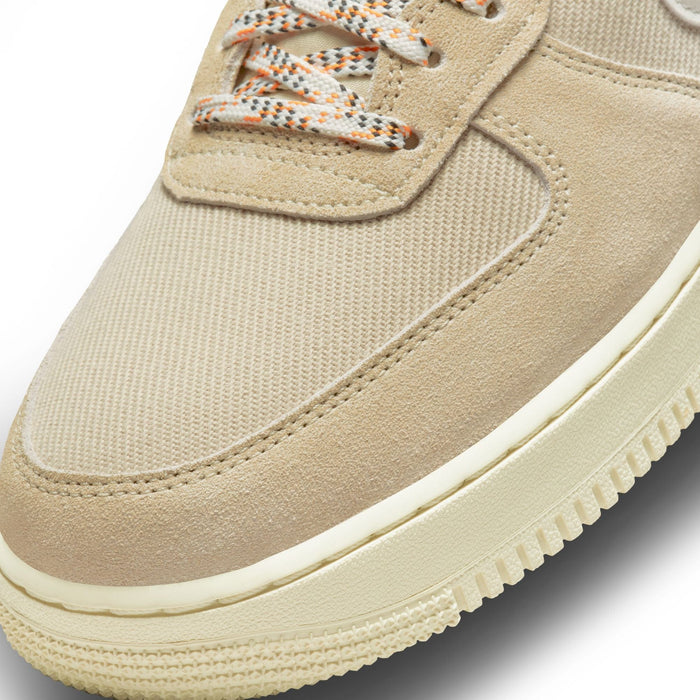 Nike Air Force 1 '07 LV8 sneakers in beige suede and canvas with orange-accented laces, close-up of toe box and midsole.