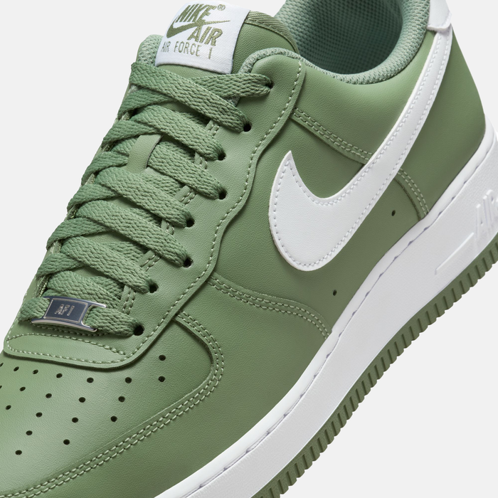 Nike Air Force 1 '07 sneakers in green leather with perforated toe box, white Swoosh logo, and green laces, angled front view.