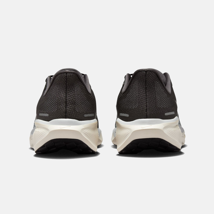 Black running shoes with white soles on a light gray background