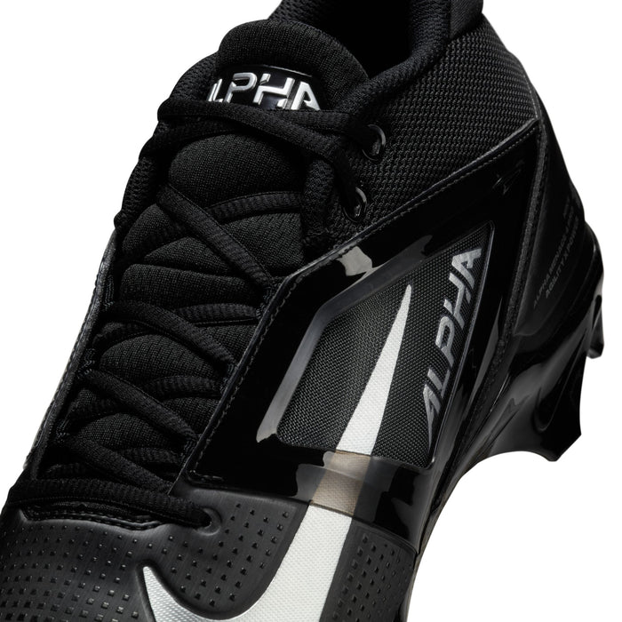Nike Alpha Menace Elite 4 football cleats in black with mesh upper, shiny synthetic overlays, and bold "Alpha" branding, close-up perspective.