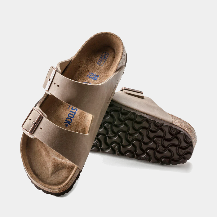 Birkenstock Arizona Soft Footbed Oiled Leather sandals in brown with adjustable straps and contoured cork sole, angled view showing upper and outsole.