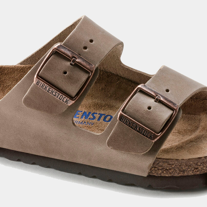 Birkenstock Arizona Soft Footbed Oiled Leather sandals in taupe with adjustable copper-tone buckles and suede-lined footbed, close-up view.