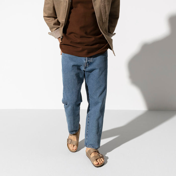 Birkenstock Arizona Soft Footbed Oiled Leather sandals in tan with adjustable buckles and contoured footbed, worn by person walking.
