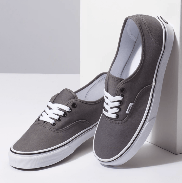 Vans Authentic sneakers in dark gray canvas with white lace-up closure and rubber outsole, angled front view.