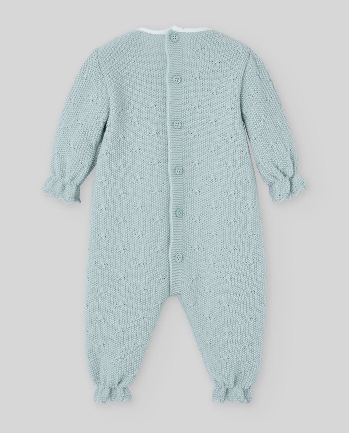 Light blue knitted baby romper with star pattern on a light gray background