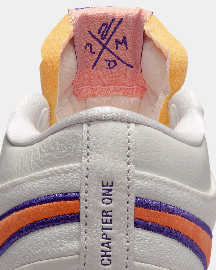 Nike Book 1 Decade shoes featuring a white leather upper, orange and purple embroidered stripes, and "Chapter One" text on the heel loop, close-up rear view.