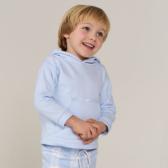 Child wearing a light blue hoodie against a plain background