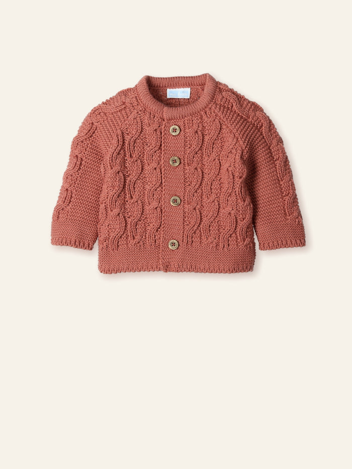 Knitted baby cardigan with cable pattern on a beige background