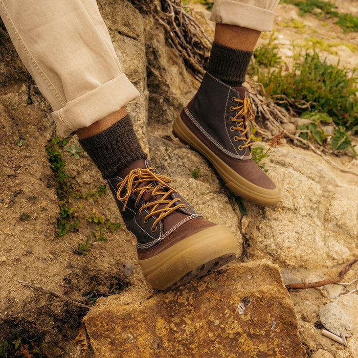 SeaVees Cascade Range Boot in brown and black with durable canvas upper, rubber outsole, and yellow laces, worn outdoors on rocky terrain.