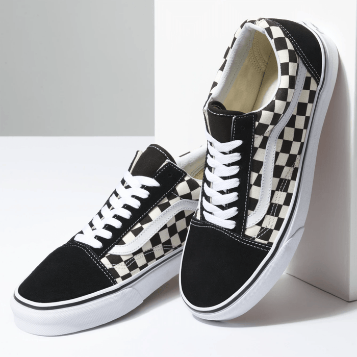 Vans Checkerboard Old Skool sneakers featuring black suede upper, white checkerboard canvas panels, and white laces, angled front view.