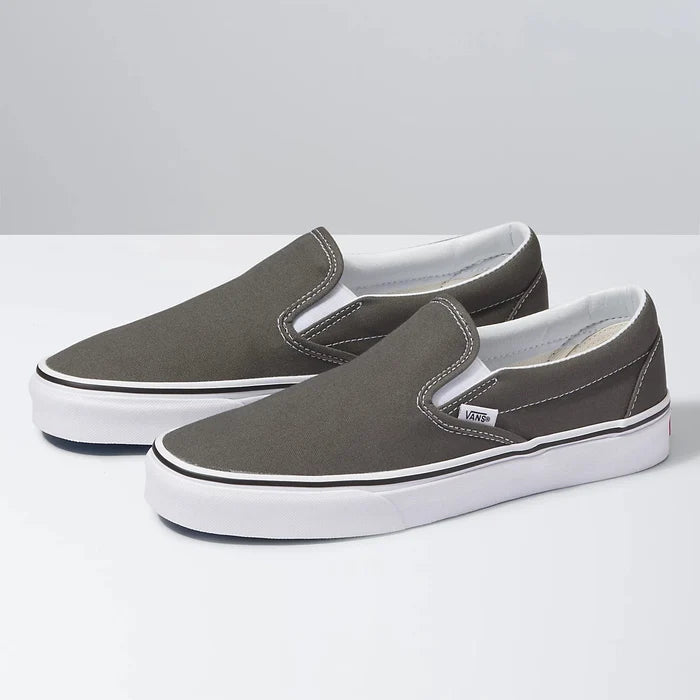 Vans Classic Slip On shoes in gray canvas with white stitching and rubber outsole, angled side view.