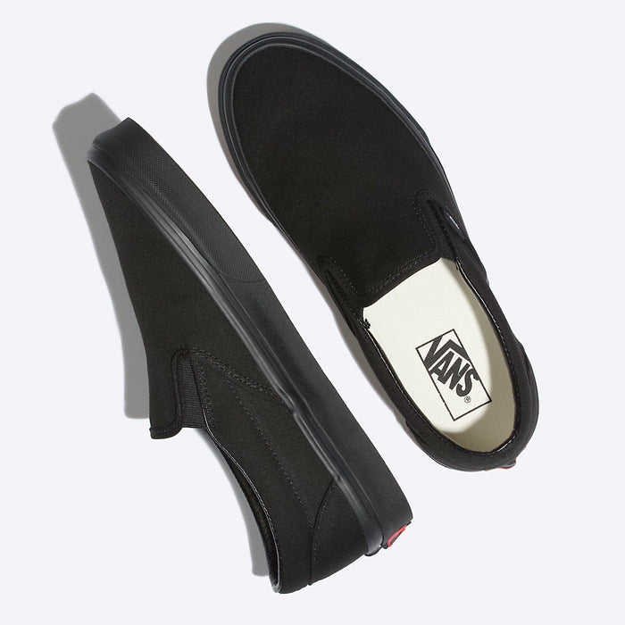 Vans Classic Slip On shoes in black canvas with elastic side accents and rubber outsole, top and angled side view.
