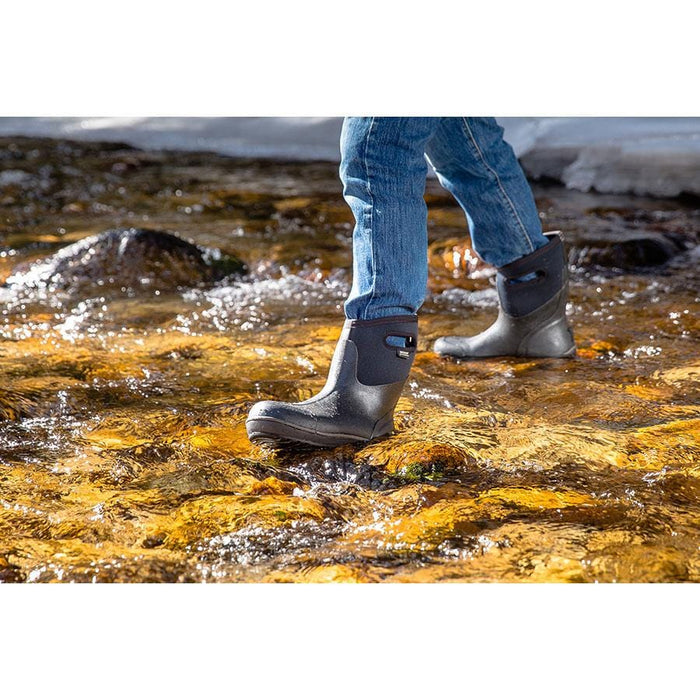 Bogs Classic Ultra High waterproof boots in black with pull handles, worn by individual walking through a stream.