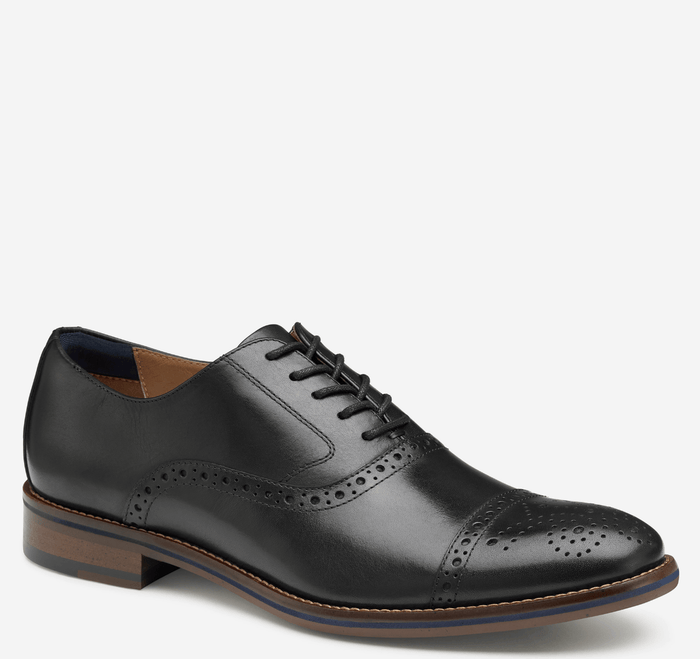 Johnston & Murphy Conard Cap Toe dress shoes in black leather with brogue perforations, lace-up closure, and stacked wooden sole, side view.