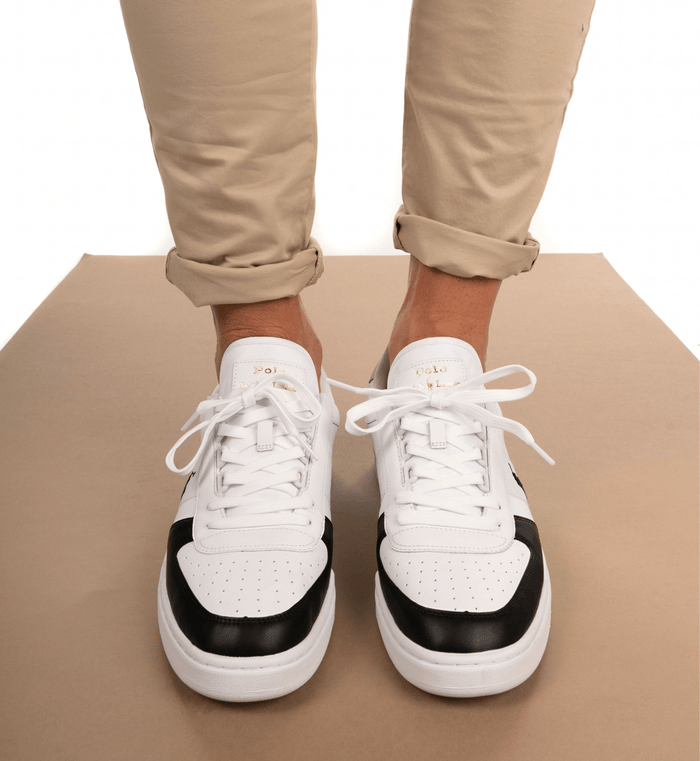 Polo Ralph Lauren Court PP sneakers in white leather with black toe cap accents, gold logo details, and lace-up closure, front view worn.