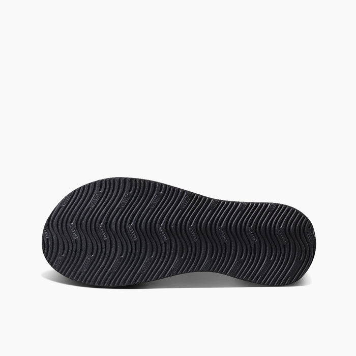 Reef Cushion Phantom 2.0 sandal outsole in black showing wave-like tread pattern for enhanced grip, bottom view.