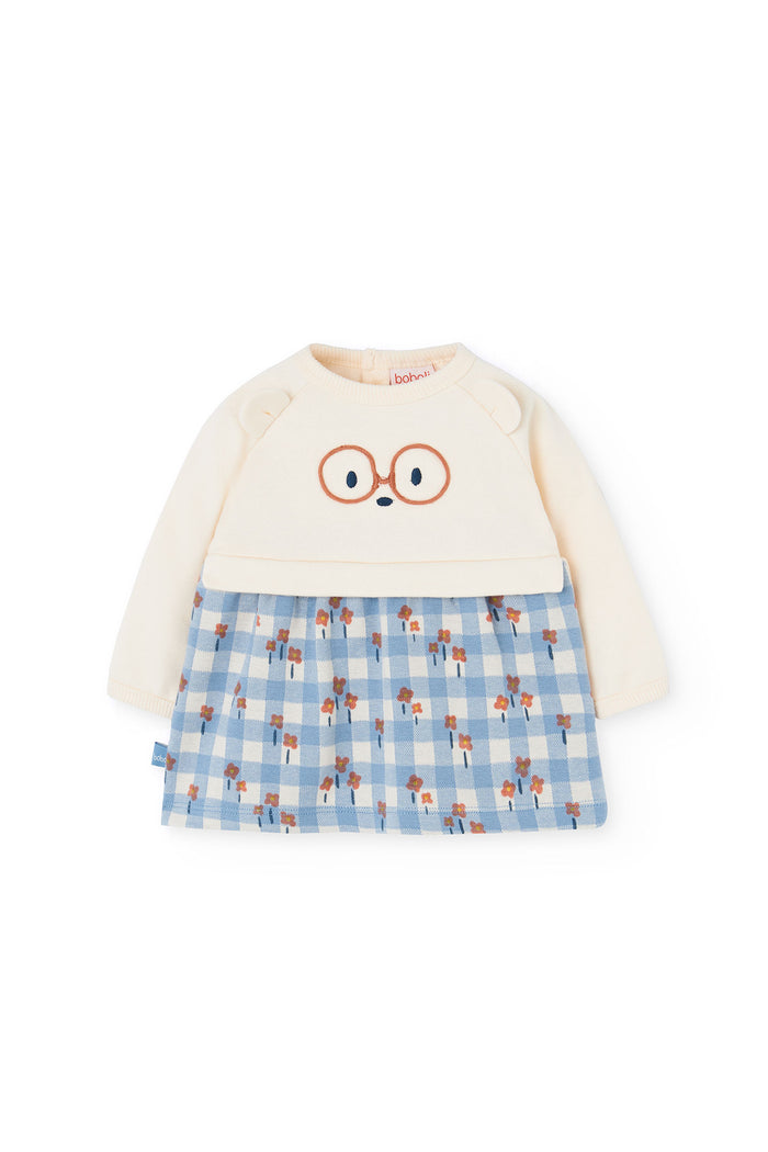 Children's outfit with cream top and blue checkered skirt on a white background