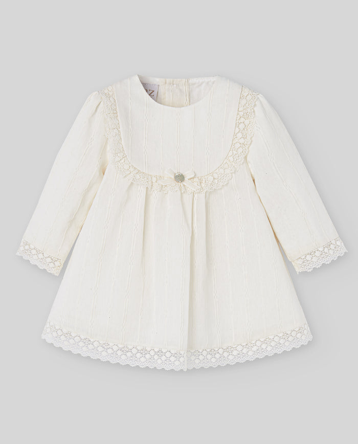 White baby dress with lace details on a gray background