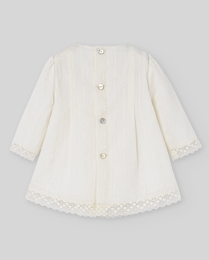 White baby coat with lace details on a gray background