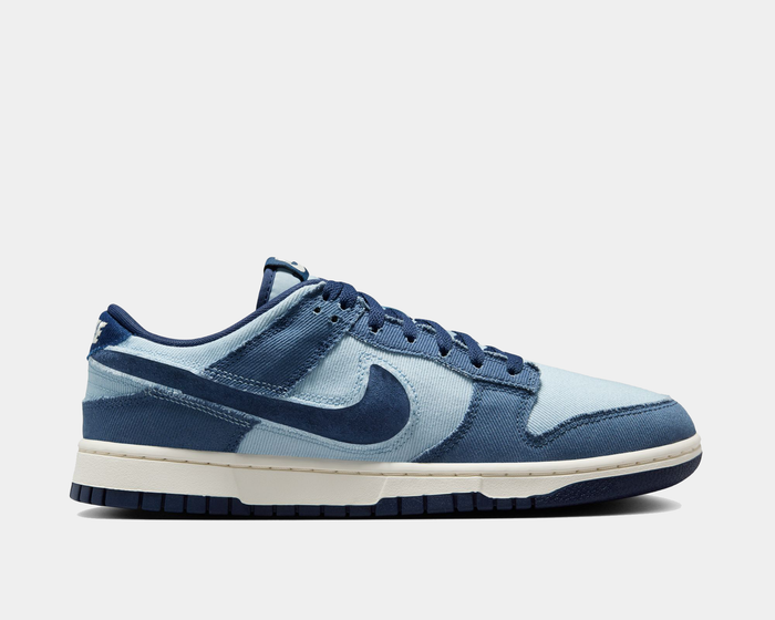 Nike Dunk Low Retro SE sneakers in light blue and navy with canvas upper and suede overlays, side view showing signature Swoosh logo.