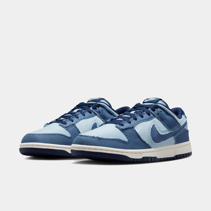 Nike Dunk Low Retro SE sneakers in light blue and navy denim with white midsole and navy outsole, front angle view.