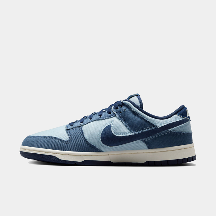 Nike Dunk Low Retro SE sneakers in light blue and navy with canvas upper, suede overlays, and white midsole, side view.