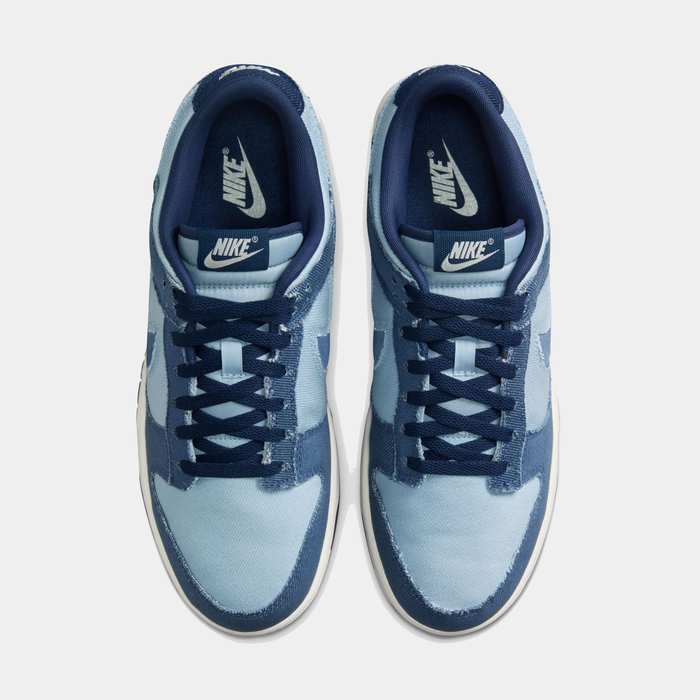 Nike Dunk Low Retro SE sneakers in light blue and navy blue denim material with white midsoles, top view showing lace-up design and branding.